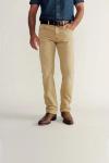 A person wearing a blue denim shirt, tan pants, brown belt, and brown boots stands against a plain background with one hand in their pocket.