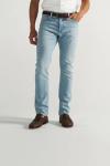 A person wearing light blue jeans, a brown belt, brown shoes, and a white shirt stands against a plain background.
