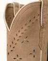 Close-up of a tan suede cowboy boot with decorative stitching and cutout patterns along the upper shaft.