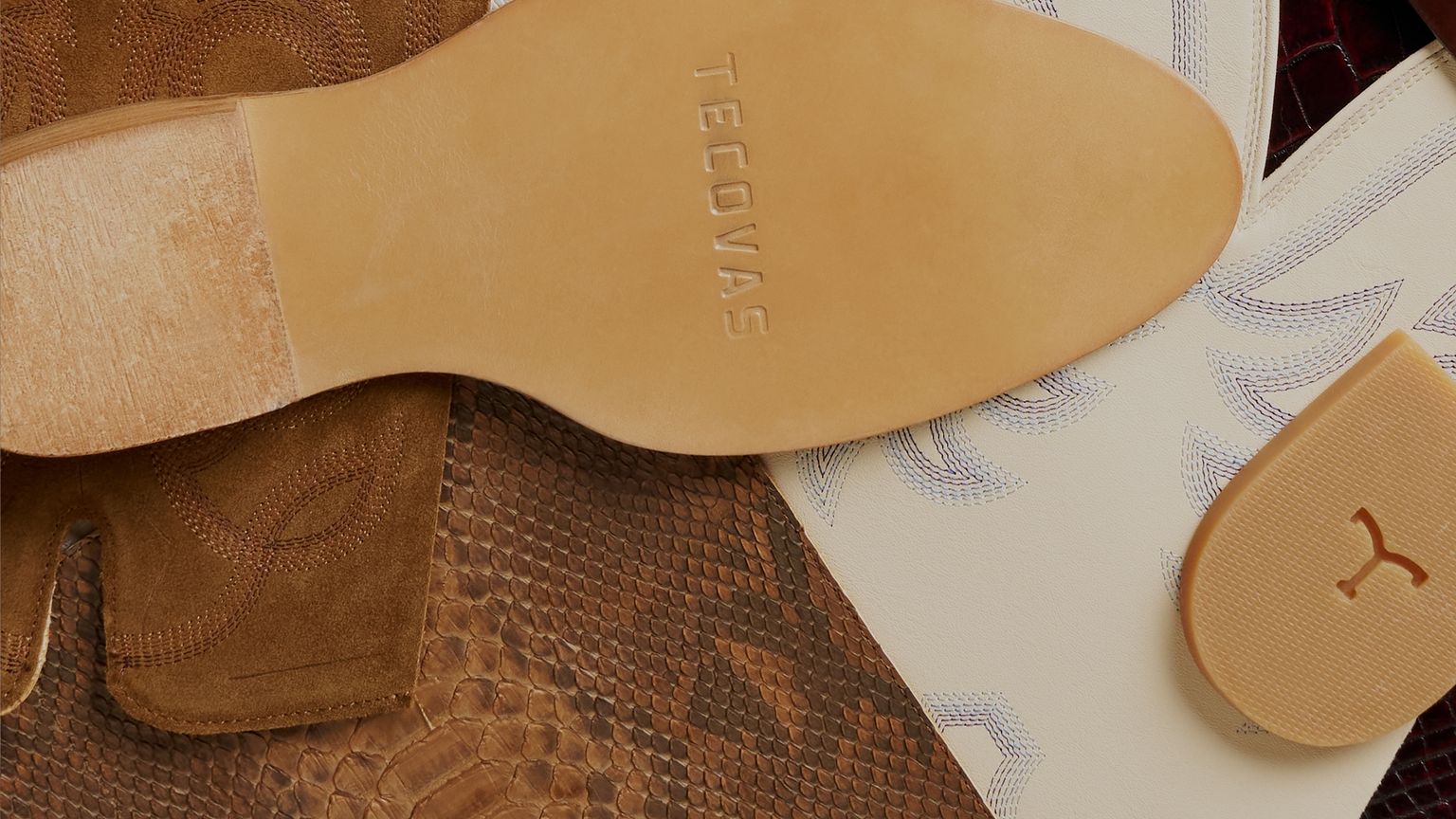 Close-up of cowboy boots with different textures and patterns, including a tan sole stamped “Tecovas,” white leather with stitching, brown suede, and reptile-embossed leather.
