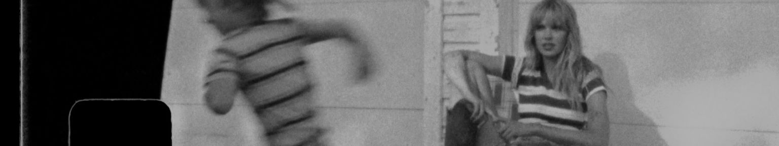 Black and white photo showing a person sitting on steps in front of a building, while another person runs past in the foreground.
