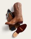 A tan snakeskin cowboy boot with a leather sole, black boot tags with “ABC,” a leather piece, and a heel insert arranged on a light background.