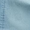 Close-up of light blue denim fabric showing a seam with visible stitching on the left side.