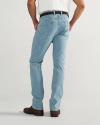 A person wearing light blue jeans, a white shirt, a brown belt, and brown shoes stands facing away from the camera.