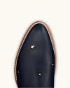 Close-up of the toe of a dark blue leather shoe with small silver star-shaped studs and a light brown welted sole.