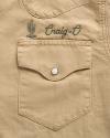 Tan shirt pocket with a buttoned flap. Above the pocket, green embroidery shows a cactus and the text “Craig-O.”.