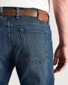A person wearing blue jeans with a brown leather belt, shown from the back waist down.