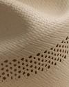 Close-up of a woven straw hat showing detailed patterns, including solid and open-weave sections, in natural beige color.