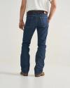 A person wearing a white shirt, blue jeans, brown belt, and brown shoes is standing facing away from the camera against a plain background.