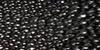Close-up view of a textured black surface with many small, shiny, irregularly shaped bumps or beads.