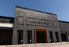 Exterior view of the Pinto Ranch store with a brick facade, large sign, and orange-framed entrance under a clear blue sky.